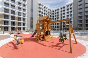 a playground with a wooden play structure on a red carpet at WeHost - Urban Oasis Modern Studio Retreat with City Views in Dubai