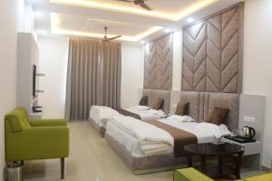 a bedroom with two beds and a green chair at Click Hotel Narayana in Ayodhya