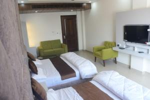 a hotel room with two beds and a flat screen tv at Click Hotel Narayana in Ayodhya