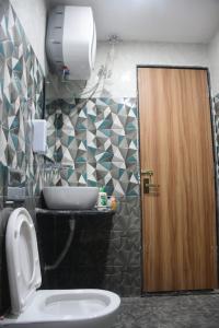 a bathroom with a toilet and a brown door at Click Hotel Narayana in Ayodhya