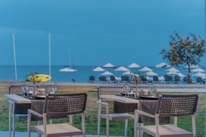 a table and chairs with tables and umbrellas on the beach at Lindos Imperial Resort & Spa in Kiotari