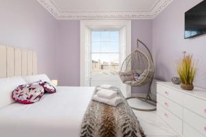 een slaapkamer met een bed, een stoel en een raam bij Spacious modern city centre apartment Castle Views in Edinburgh