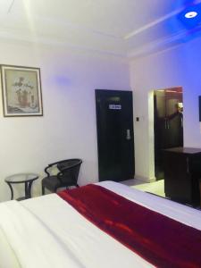 um quarto com uma cama, 2 cadeiras e uma secretária em MCLORRETS SUITES em Enugu