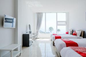 a white room with three beds and a window at OYO 1194 Villa Bukit Panderman Residence in Tlekung