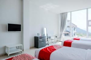 a hotel room with three beds and a television at OYO 1194 Villa Bukit Panderman Residence in Tlekung