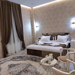a hotel room with a bed and a table and chairs at The Afrosiyob Ok in Samarkand