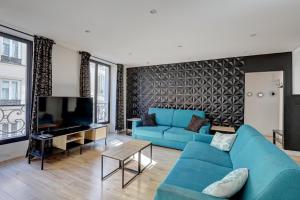 a living room with a blue couch and a television at 127 Suite Moshé - Superbe Appartement à Paris. in Paris