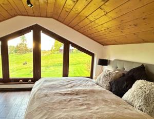 a bedroom with a large bed with a large window at Chata u Hrušků 100m od sjezdovky in Oravská Lesná