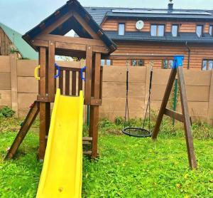 a playground with a yellow slide in the grass at Chata u Hrušků 100m od sjezdovky in Oravská Lesná