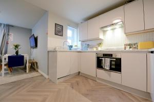 uma cozinha com armários brancos e uma bancada em 2 BEDROOM FLAT in WOOD GREEN PICCADILLY LINE em Londres