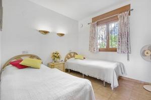 2 Betten in einem weißen Zimmer mit Fenster in der Unterkunft Casasilma in Cumbre del Sol