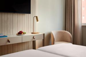 a hotel room with a bed and a chair and a tv at Dom Jose Beach Hotel (Plus) in Quarteira