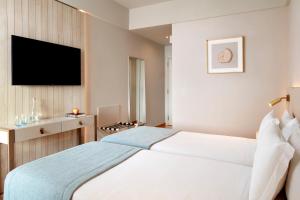 a hotel room with a bed and a flat screen tv at Dom Jose Beach Hotel (Plus) in Quarteira