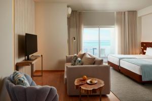 a hotel room with a bed and a couch and a tv at Dom Jose Beach Hotel (Plus) in Quarteira