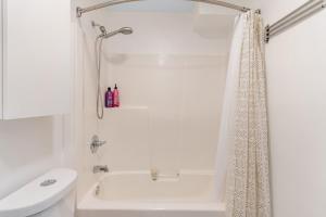 a white bathroom with a shower and a toilet at Seattle's Gem: Elegant 1BR in Belltown in Seattle +19 photos