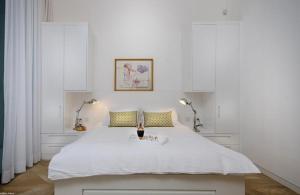 um quarto branco com uma grande cama branca e 2 candeeiros em לוויט האוס em Poriyya