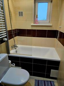 łazienka z wanną, toaletą i oknem w obiekcie Spokojne i miłe miejsce na Mazurach w mieście Kętrzyn