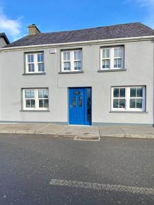 a white house with a blue door on a street at Modern family home in Castleisland