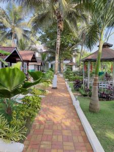 a brick pathway with palm trees in a resort at Melba Beach Resort By Maitree in Arambol