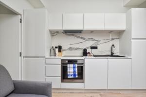 a kitchen with white cabinets and a sink at 141 Suite Klein - Superbe Appartement à Paris. in Paris