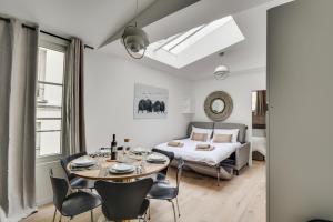 a room with a bed and a table and chairs at 141 Suite Klein - Superbe Appartement à Paris. in Paris