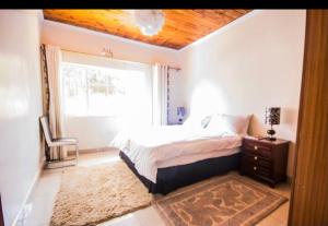 ein Schlafzimmer mit einem Bett, einem Fenster und einem Stuhl in der Unterkunft Riverfront Gardens in Mjini