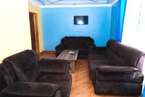 uma sala de estar com um sofá, sofás e uma mesa em Gerly Homes Hotel & Restaurant em Kakamega