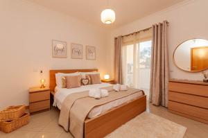 ein Schlafzimmer mit einem großen Bett und einem Spiegel in der Unterkunft Encosta da Orada by OCvillas in Albufeira + 139 Fotos