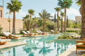 a swimming pool with lounge chairs and palm trees at Park Hyatt Marrakech in Marrakesh