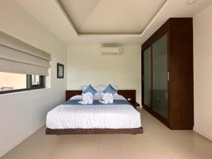 um quarto com uma cama grande e almofadas azuis em TSE Residence [by Samui Emerald] em Praia de Choeng Mon