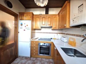 a kitchen with wooden cabinets and a white refrigerator at Dúplex familiar i amb vistes al centre d’Esterri by RURAL D'ÀNEU in Esterri d'Àneu