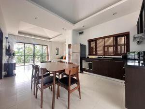 a kitchen with a wooden table and some chairs at TSE Residence [by Samui Emerald] in Choeng Mon Beach