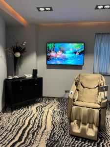 a living room with a chair and a flat screen tv at Hotel River Park in Cluj-Napoca