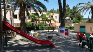 a playground with a red slide in a yard at Lido I Palmizi in Capoliveri