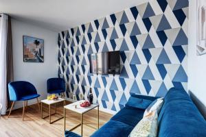 a living room with a blue couch and a geometric wall at 869-Suite Bleuet - Superb Apartment in Montreuil