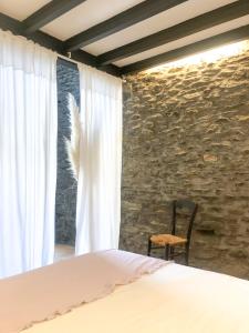 1 dormitorio con cama y pared de piedra en Paller rústic de muntanya amb estil i acollidor by RURAL D'ÀNEU, en Aydí