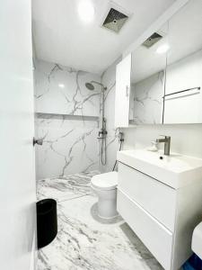 a white bathroom with a toilet and a sink at Two Bedroom Condo in BGC with Balcony, Sauna, & Pool in Manila