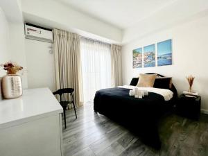 a bedroom with a black bed and a kitchen at Two Bedroom Condo in BGC with Balcony, Sauna, & Pool in Manila