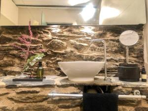encimera de baño con lavabo en una pared de piedra en Paller rústic de muntanya amb estil i acollidor by RURAL D'ÀNEU, en Aydí