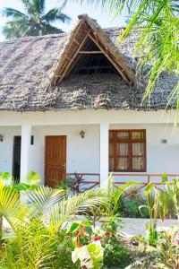 a white house with a thatch roof at Zangreen Bungalows in Jambiani