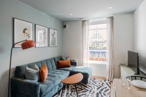 a living room with a blue couch and a window at Bijou flat on Broadway Market in London
