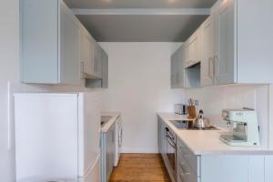 a white kitchen with white cabinets and wooden floors at Bijou flat on Broadway Market in London
