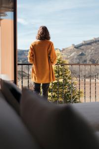 een vrouw die uit het raam van een gebouw kijkt bij Hotel Casa Cauma in Albarracín