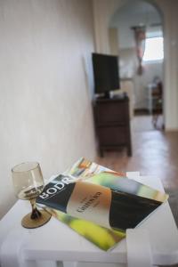 czasopismo siedzące na stole obok kieliszka wina w obiekcie Hellényi apartmanok w mieście Harkány