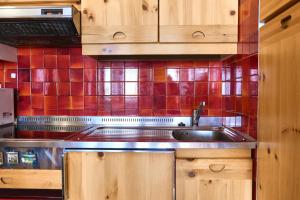 a kitchen with a sink and a red tiled wall at Villa Antermont in Canazei