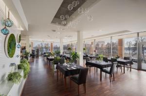 um restaurante com mesas e cadeiras pretas e janelas em Hotel Moran & SPA em Powidz