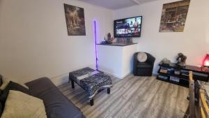 a living room with a couch and a purple lightsaber at Appartement Rethel - Netflix - Marc & cécile in Rethel