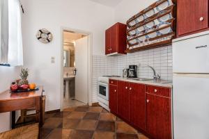 a kitchen with red cabinets and a sink and a refrigerator at Melisses Sea View Studio in Plaka Milou +4 photos