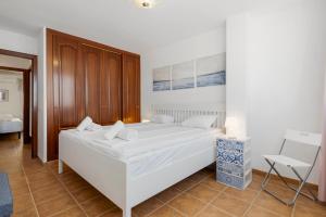 a bedroom with a large white bed and a chair at Smart flat close to Fuengirola beach - Ref 94 in Fuengirola