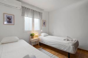 two beds in a room with white walls and a window at Smart flat close to Fuengirola beach - Ref 94 in Fuengirola